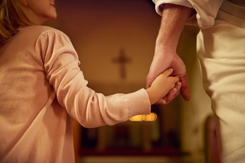 Cropped shot of a little girl holding hands with Jesus while standing inside a church